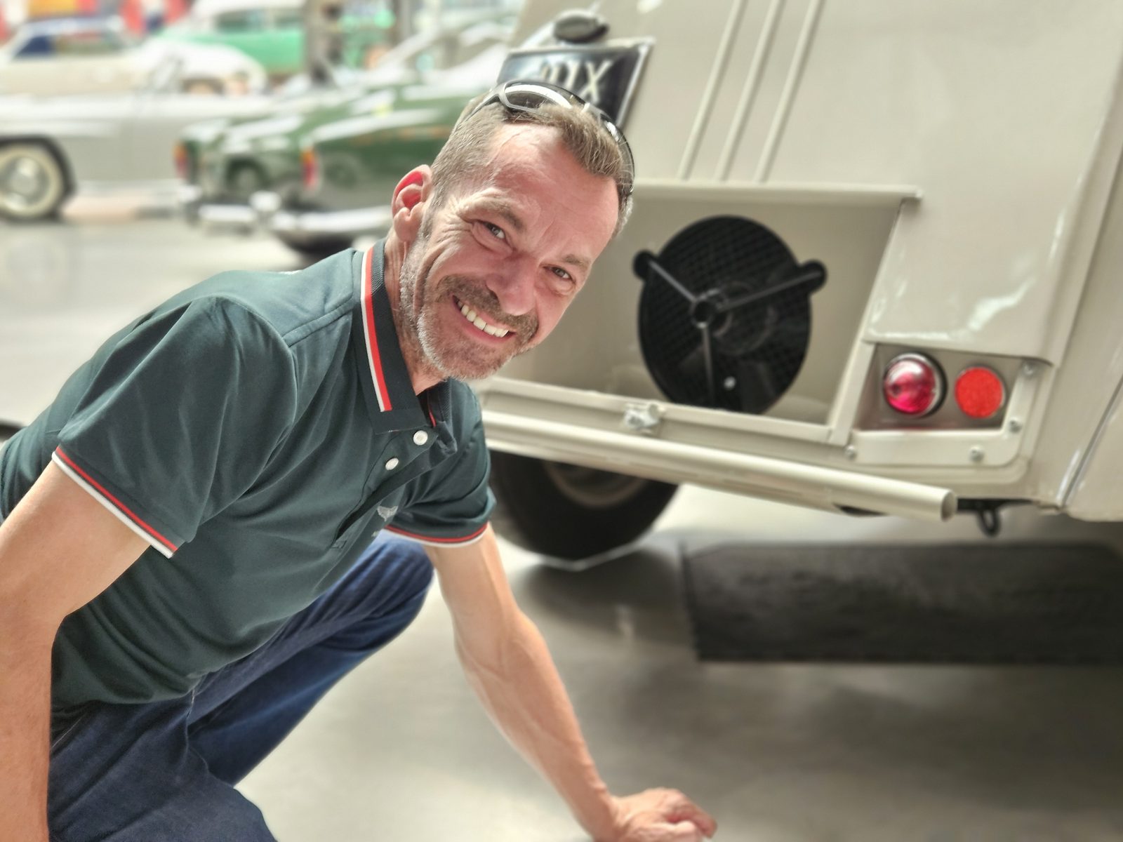 Harry lächelnd neben einem Oldtimer